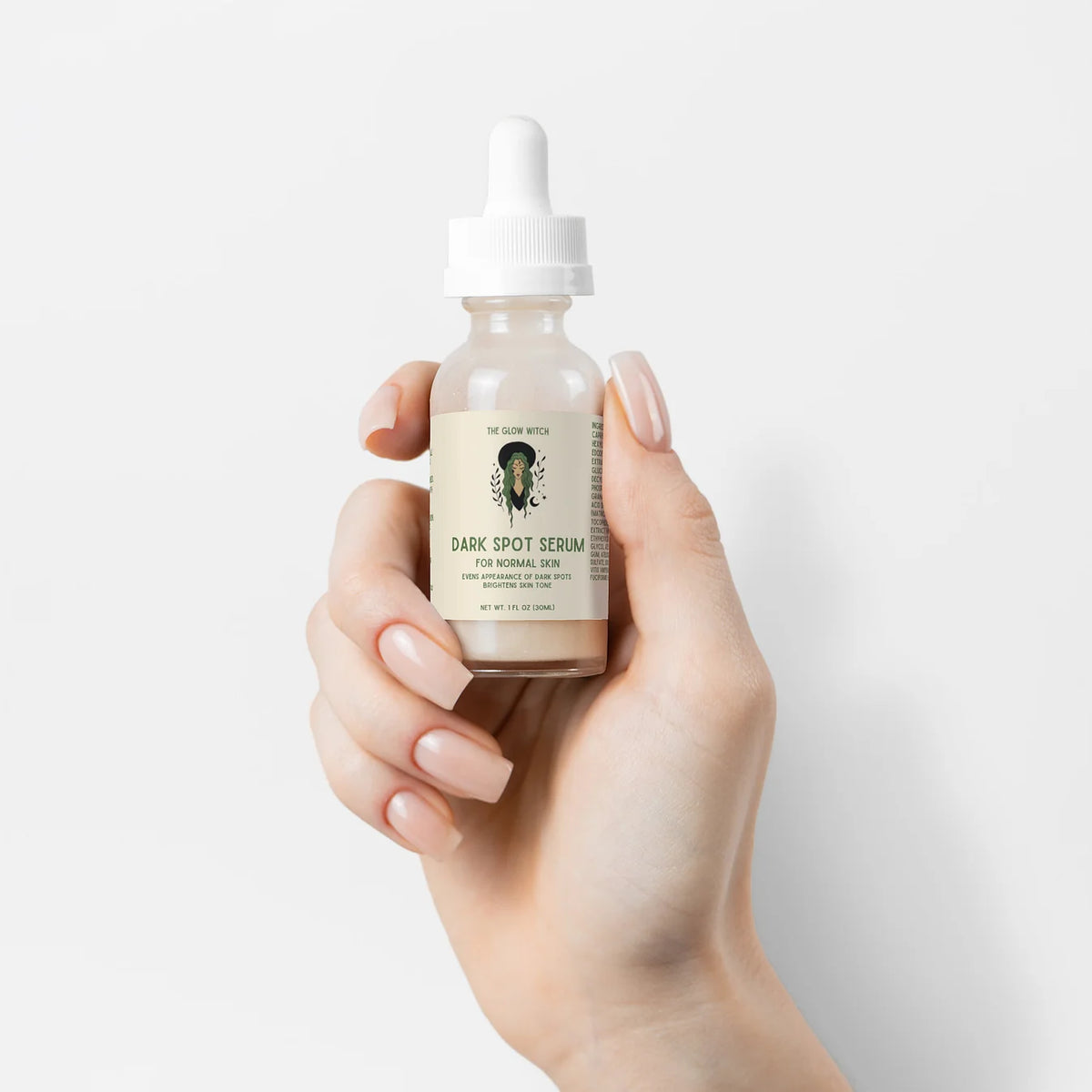 A hand with manicured nails holds a small glass dropper bottle of Dr. Gable's Dark Spot Serum against a clean white background.